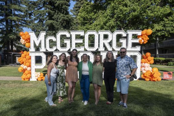 A group of individuals stand in front of a sign and pose for a photo.